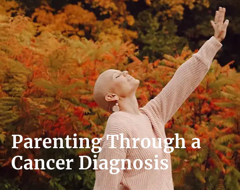 Woman with a shaved head raising her arm outdoors among autumn foliage, symbolizing strength and hope, with the text “Parenting Through a Cancer Diagnosis.”